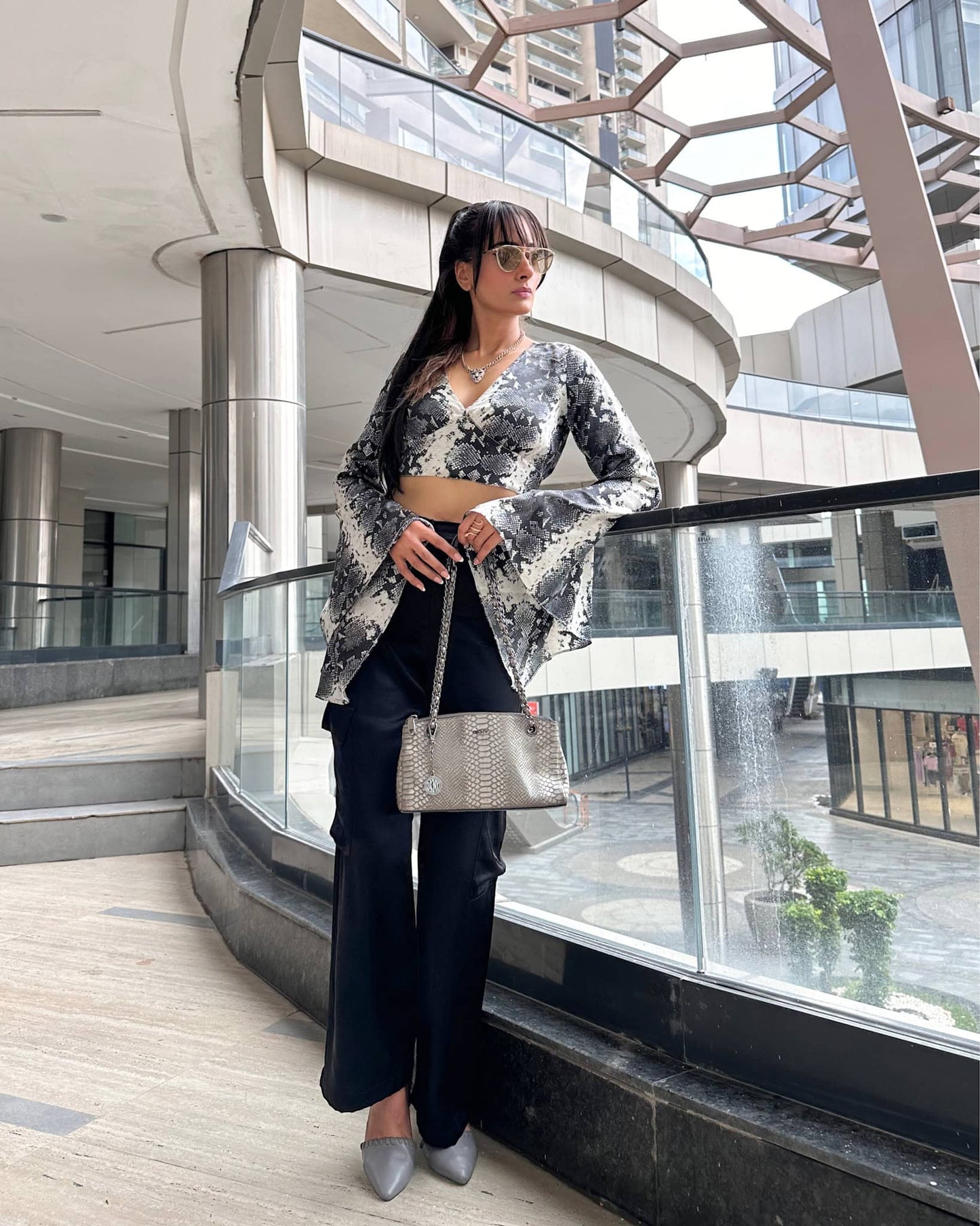 Model wearing a V neck crop top with long flared sleeves in snake skin print, crafted from smooth satin with a side zip closure.