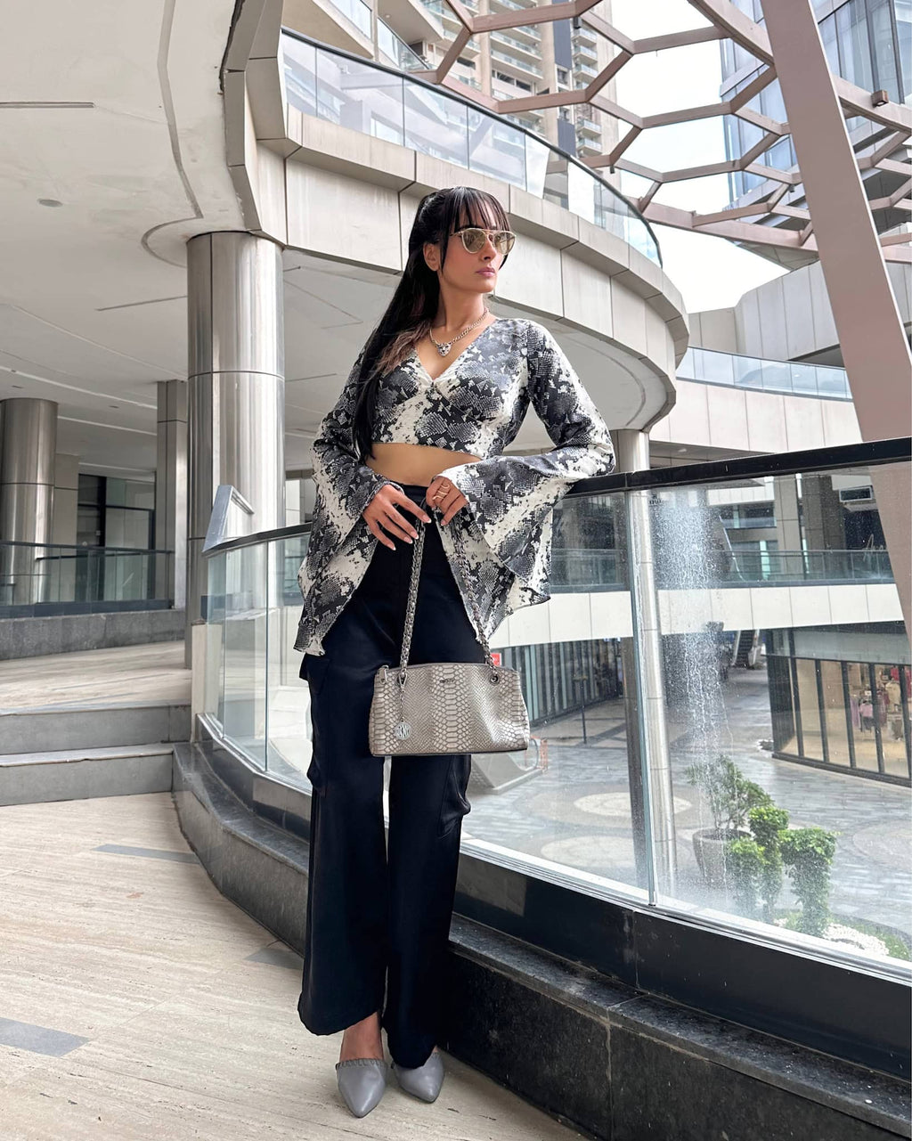 Model wearing a V neck crop top with long flared sleeves in snake skin print, crafted from smooth satin with a side zip closure.