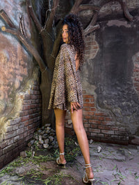 Model wearing a leopard print dress mini with A-line silhouette, deep back, V-neckline, and full flared sleeves in flowy fabric.